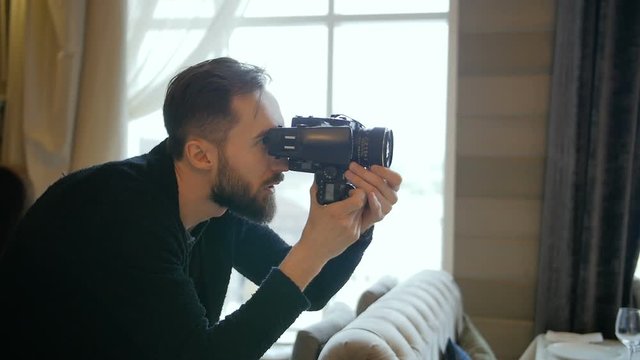 Photographer composing and framing image, focusing and shooting with medium format film camera in studio, professional male artist working with portrait angle lens