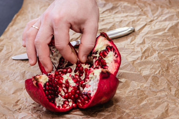 Chopped ripe pomegranate, man's hands, pomegranate fruit, close-up