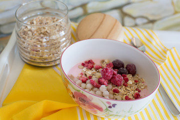 healthy breakfast with natural yogurt, muesli and berries in plate in flower on white tray