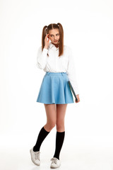 Young emotional pretty girl in uniform posing over white background.