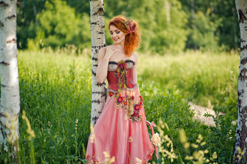 Woman in red dress walking at the summer nature.