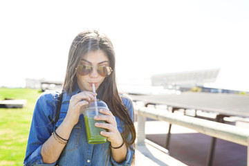 Spain, Barcelona, young woman drinking green beverage