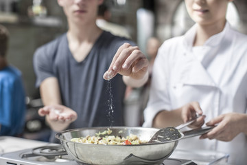 Teenager adding salt to pan