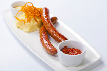 Sausage with potatoes and sauerkraut on a white plate