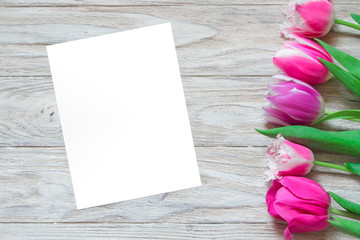 Several tulips on the right side of wooden background and white paper