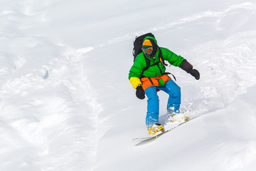 Naklejka na ściany i meble snowboarder snowboarding on fresh snow on ski slope on Sunny winter day in the ski resort in Georgia