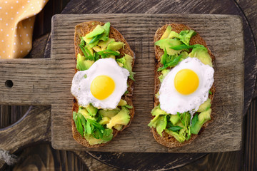 avocado quail egg sandwiches in a plate on a wooden cutting board