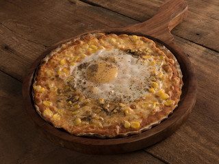 bulls eye corn pizza served in a wooden plate on wooden background
