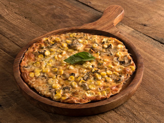 funghi corn pizza served in a wooden plate on wooden background