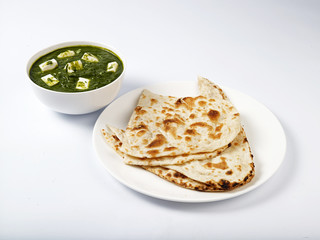 Palak Paneer gravy served with naan on a white background