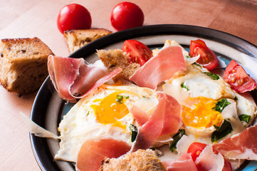Breakfast of eggs and jamon and tomatoes.