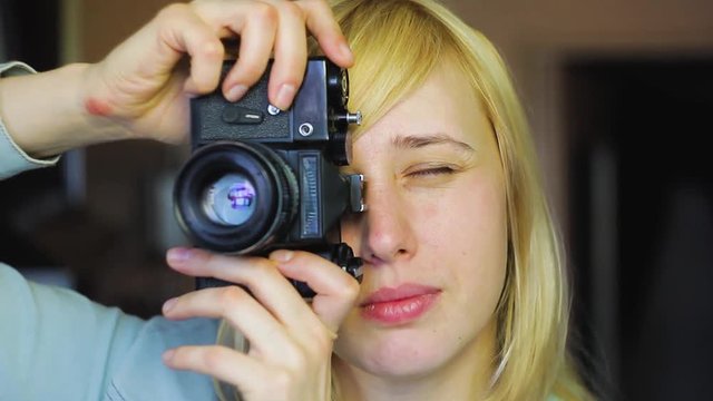 Blonde with different eyes shoots on an old retro camera, heterochromia