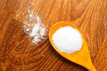 Salt in wooden spoon on wooden background