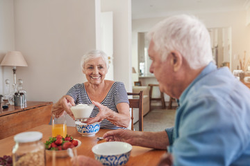 Fototapeta na wymiar Content seniors eating a healthy breakfast together at home