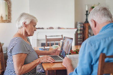 Seniors spending time online and reading the newspaper at home