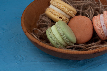 Closeup Assortment macaroons in wooden plate on a blue background