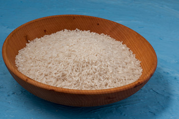 plain rice in wooden bowl over blue background