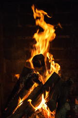 A large flame burns the firewood for the barbecue