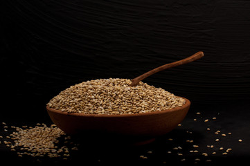 Whole grain of pearl barley or wheat spill on right black background. Agriculture food raw seed.
