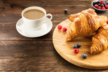 Fresh croissants with blueberries, raspberries, and latte