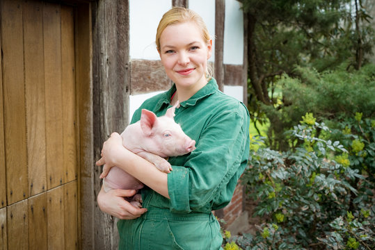 Imagepflege in der Schweinehaltung - junge Landwirtin mit Ferkel im Arm