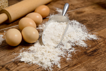 Flour, eggs and rolling pin on wooden table