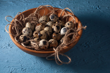 quail eggs in wooden bowl isolated on blue background close up