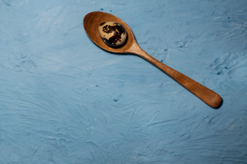 quail eggs in wooden spoons on blue textured background