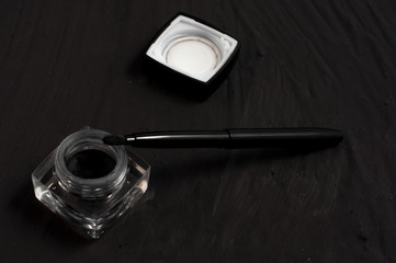 Eyeliner and brush on black background.