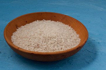 plain rice in wooden bowl over blue background