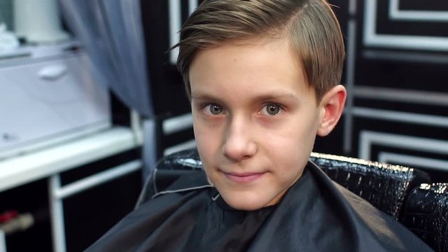 Portrait of a boy with a beautiful haircut in a hairdresser, slow motion.