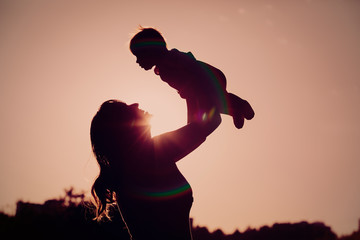 mother and little newborn daughter silhouettes at sunset