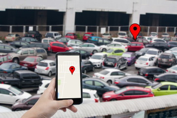 car finder via gps - hand hold smartphone with blur parking lot