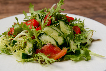 Vegetable salad in white round plate on wooden table. Macro.