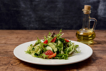 Vegetable salad in white round plate on wooden table. Macro.