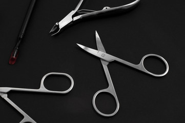 set of metallic manicure tools on a black background