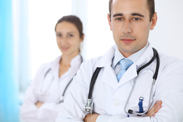 Fototapeta premium Cheerful smiling male doctor with medical staff at the hospital