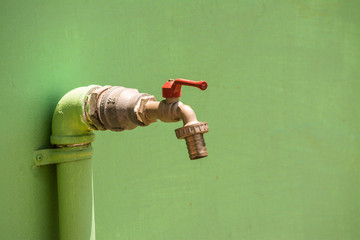 The faucet is attached to a bright green wall.