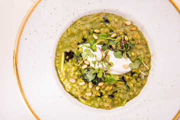 Orzotto with goat cheese and spinach in a round plate on a white cloth