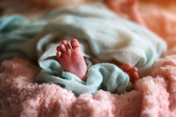 Little cute newborn baby feets in the bed