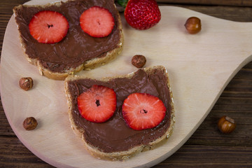 Bread with chocolate cream and strawberry on a wooden board