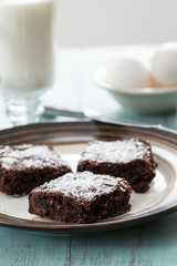 A Plate of Three Brownies With Eggs and Milk