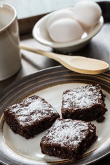 A Plate of Brownies with a Wooden Spoon and Eggs