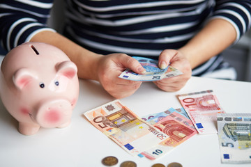 Close up of a pregnant woman behind the desk counting money