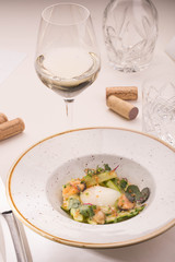 Table layout with giving of an asparagus with sauce, goose egg and mussels. Glass of white wine