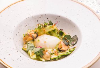 The asparagus with mussels and goose egg sauced ber-blan in a round plate on a table