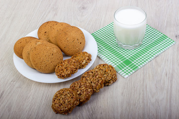 A glass of milk, and assorted cookies on the table.