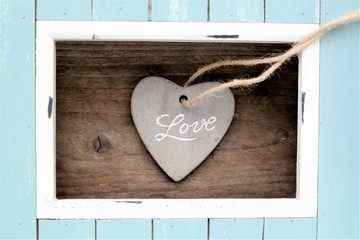 light blue and white colored wood frame and stone heart with the word love with natural wooden background, Father's Day, Mother’s day, Valentine or anniversary