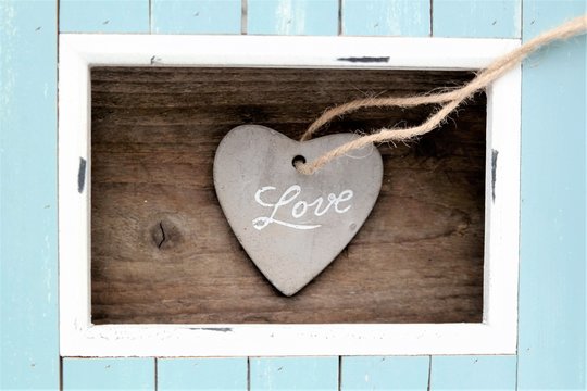 light blue and white colored wood frame and stone heart with the word love with natural wooden background, Father's Day, Mother’s day, Valentine or anniversary