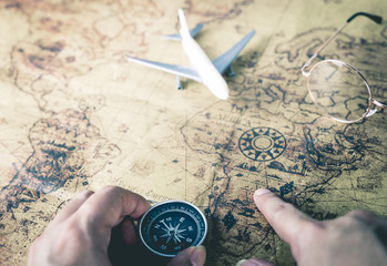Traveler is using compass and vintage map to plan his travel